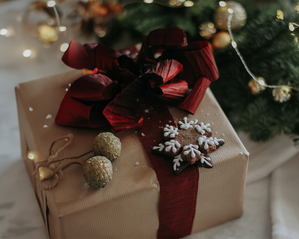 Jõulukingitus, mis on pakitud paberisse, seotud paelaga ja kaunistatud küpsisega.