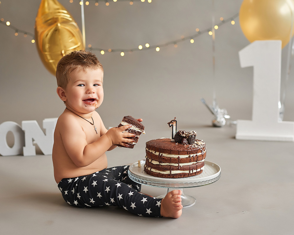 Üheaastane poiss hoiab oma sünnipäeval käes šokolaaditordi lõiku