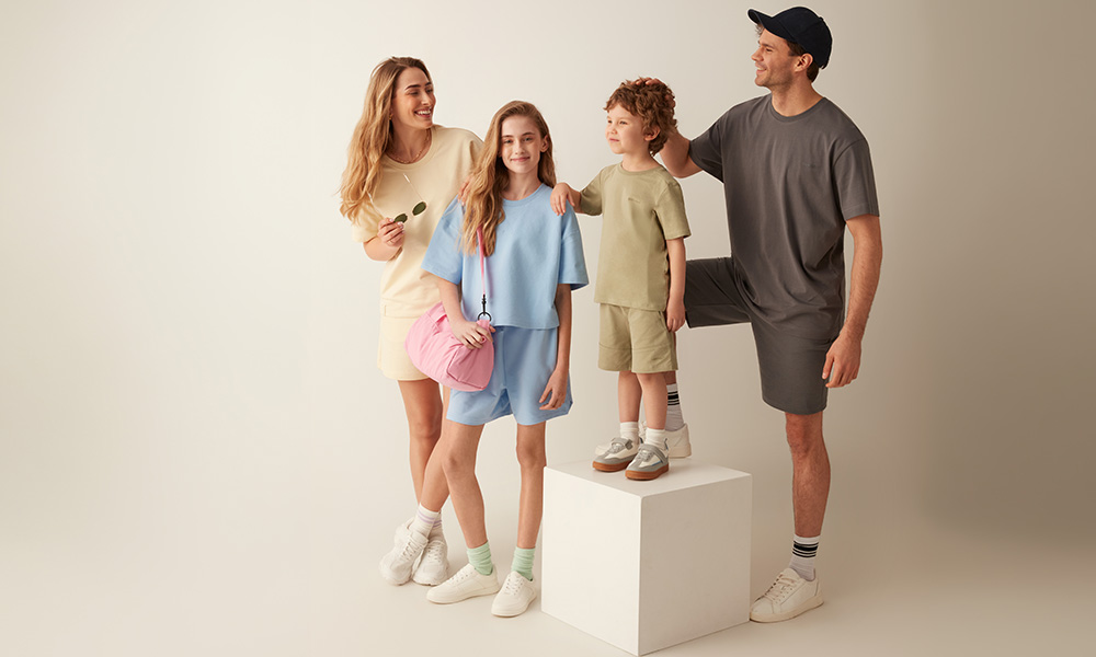 Pastelsetes riietes perekond poseerib koos heledal taustal.